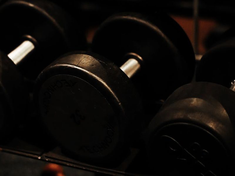 Dark atmospheric gym with weights and heavy chains.